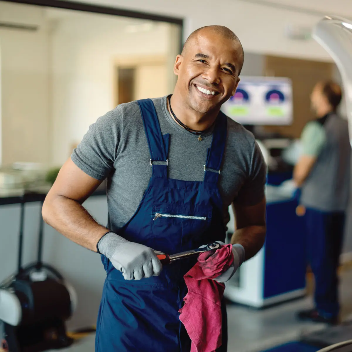 Smiling mechanic holding a tool
